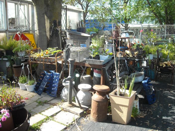 old water pump on wooden base , lots of asst concrete pots, milkcans , benches and more